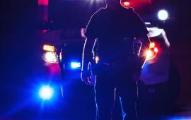 Police officer at night with car behind