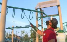 man sanitizing playground equipment