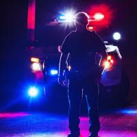 Police officer at night with car behind