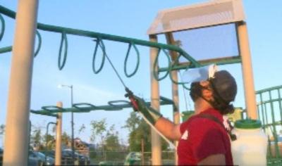 man sanitizing playground equipment